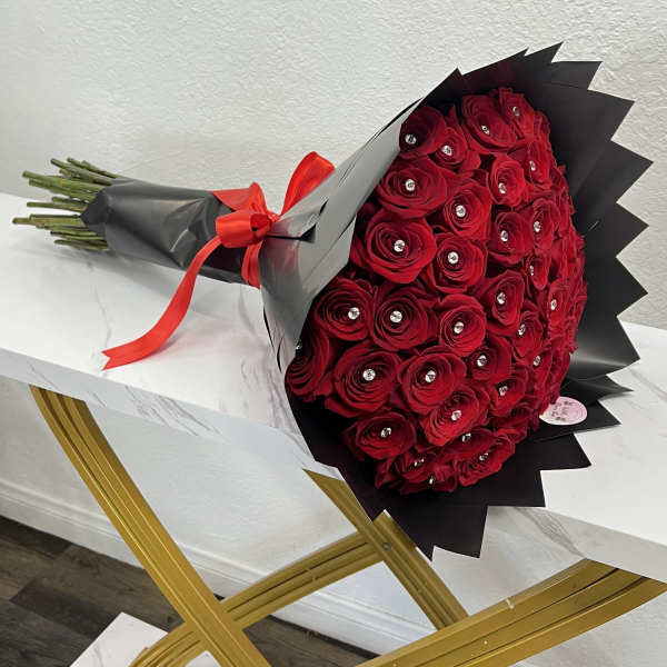 Bouquet of red roses wrapped in black paper with a red ribbon