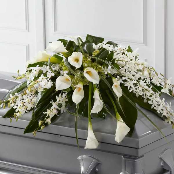White calla lilies and orchids arranged on a casket