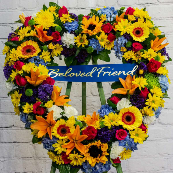 Heart-shaped floral wreath with a "Beloved Friend" ribbon
