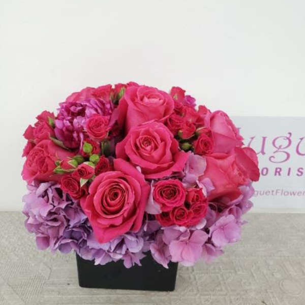 Pink roses and hydrangeas arranged in a black square vase
