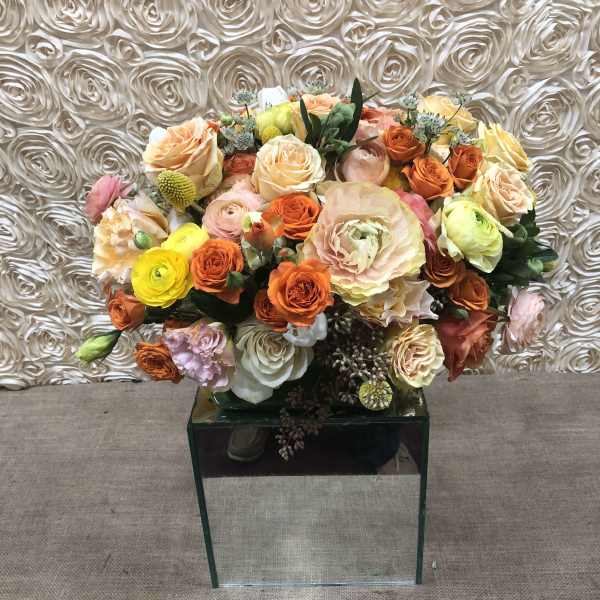 Mixed bouquet of roses and ranunculus in a mirrored cube vase