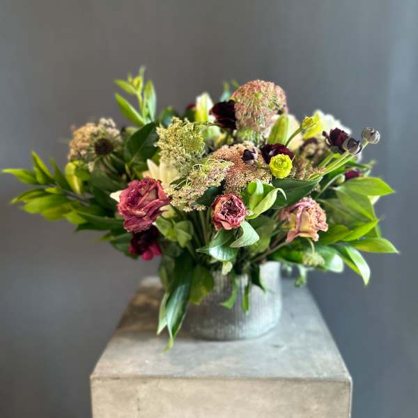 Mixed bouquet in a ribbed metal vase with burgundy and pale pink blooms