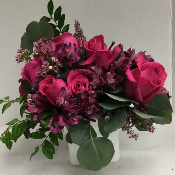 Pink roses and purple flowers arranged in a white vase