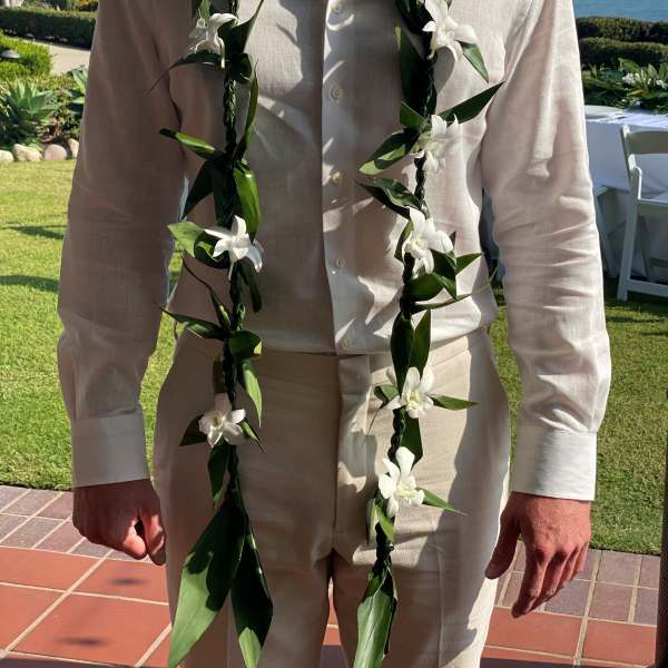 Man wearing a white shirt with two white floral leis