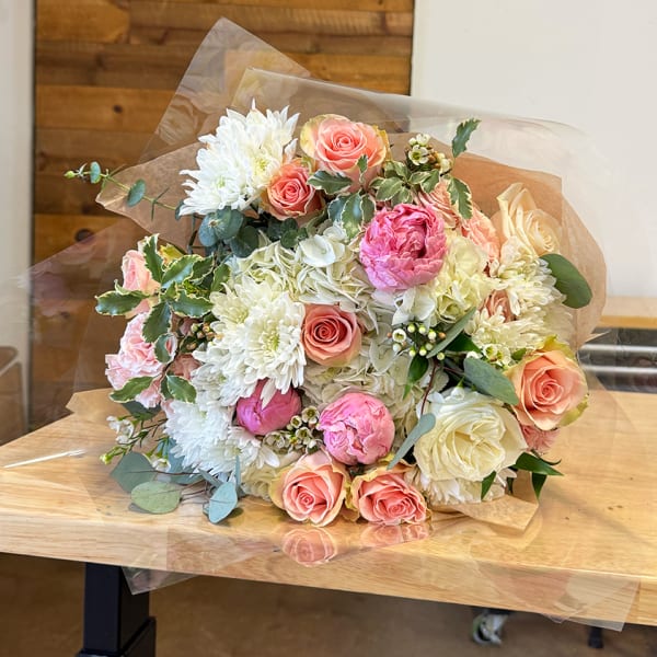 Bouquet of pink and white roses with white chrysanthemums wrapped in clear paper