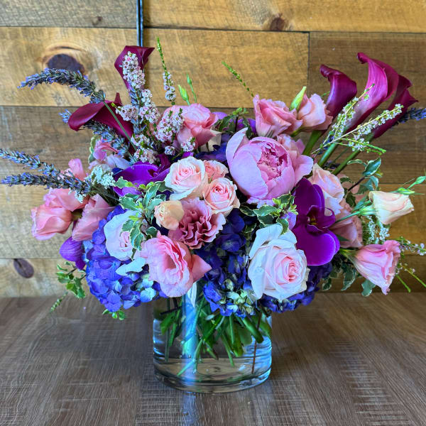 Mixed pink and purple floral arrangement in a clear glass vase