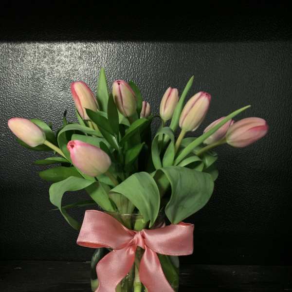 Pink tulips in a glass vase with a pink ribbon bow