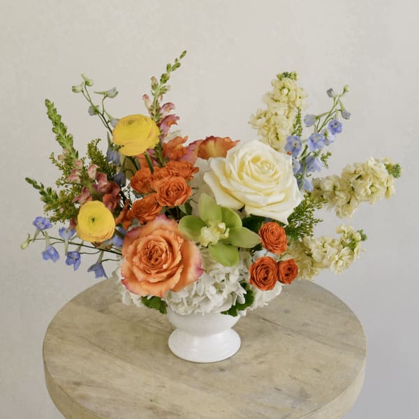 Colorful mixed flower arrangement in a white pedestal vase