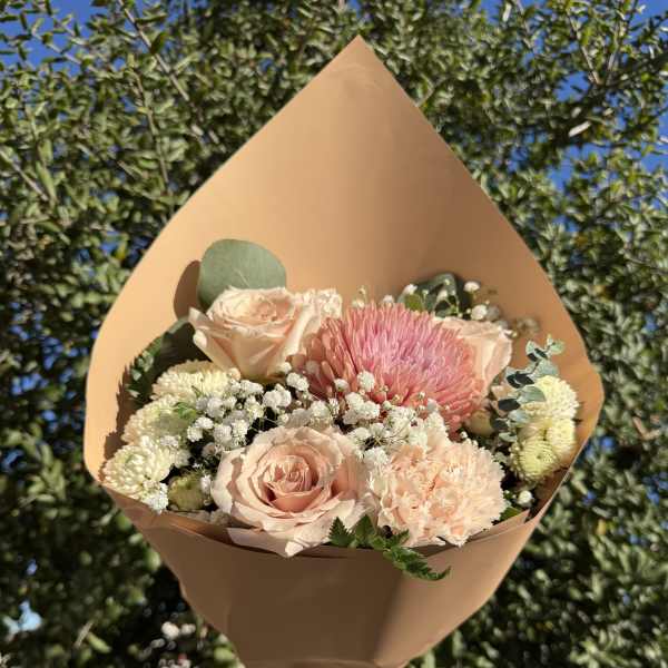 Bouquet of blush roses, pink chrysanthemum, and white filler flowers in tan wrap