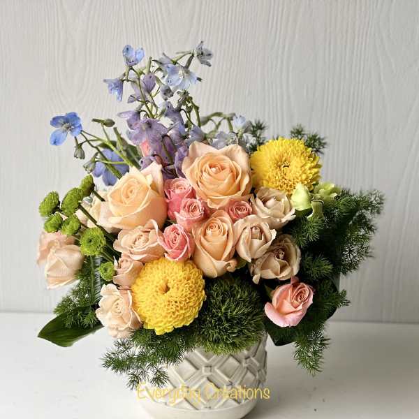 Peach and pink roses with yellow mums in a white vase