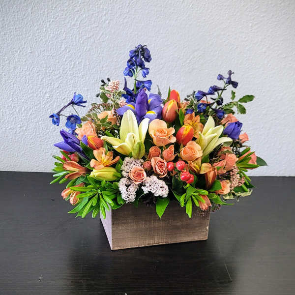 Mixed bouquet in a wooden box with peach, purple, and white flowers