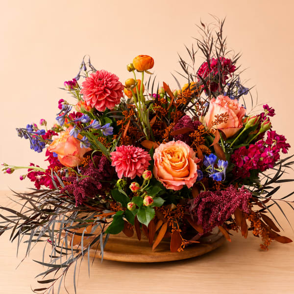 Colorful mixed flower arrangement in a low wooden bowl