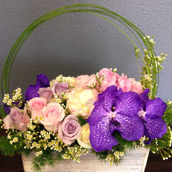 Pink and lavender roses with purple orchids in a rectangular wooden container