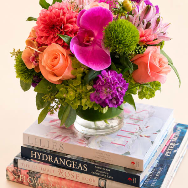 Mixed bouquet of pink, coral, and purple flowers in a glass vase