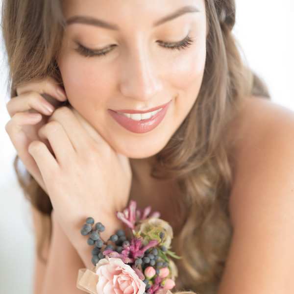 Woman wearing a floral wrist corsage with pink blooms and ribbon