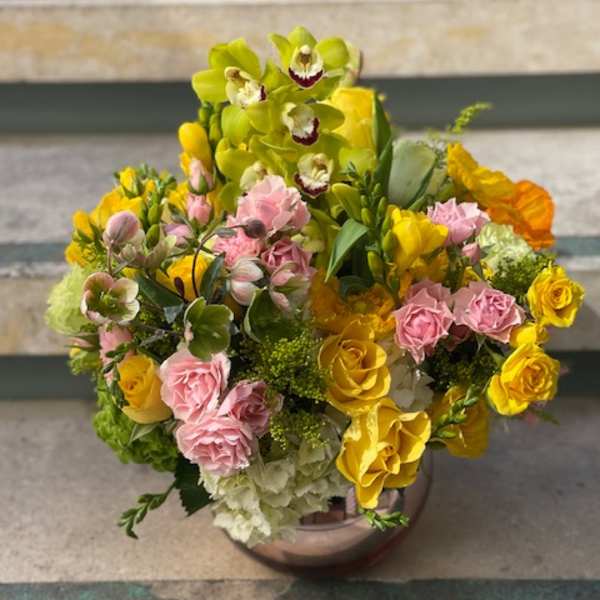 Bouquet of yellow orchids, pink roses, and green hydrangeas in a vase