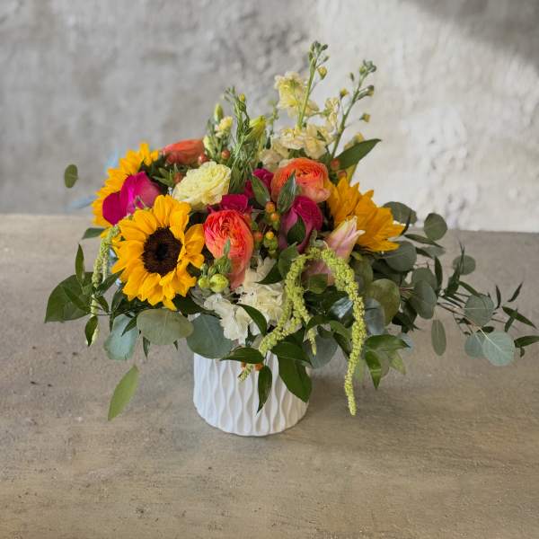 Mixed bouquet in a white textured vase with sunflowers and bright pink blooms