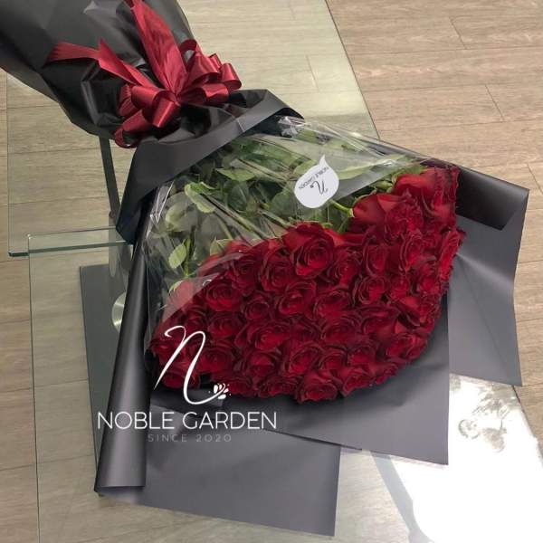 Bouquet of red roses wrapped in black paper with a red ribbon