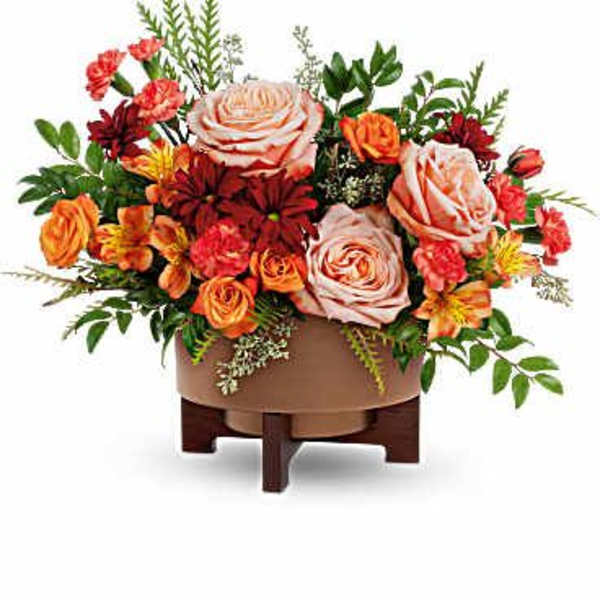 Arrangement of peach and orange roses with mixed flowers in a low wooden container