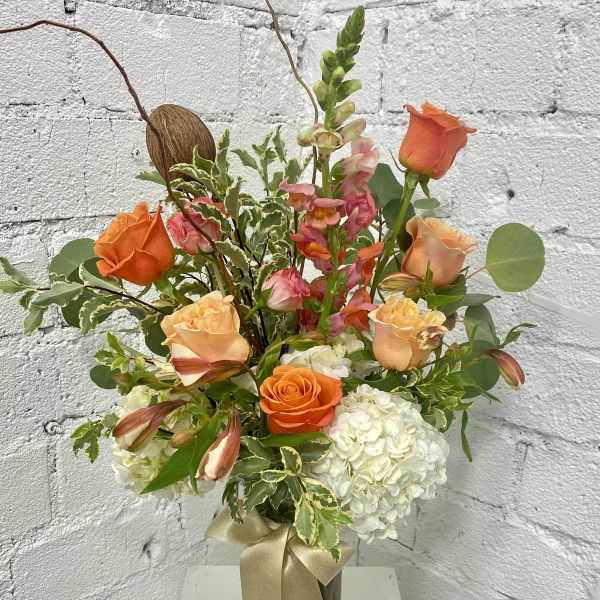 Orange and peach roses with white hydrangeas in a glass vase