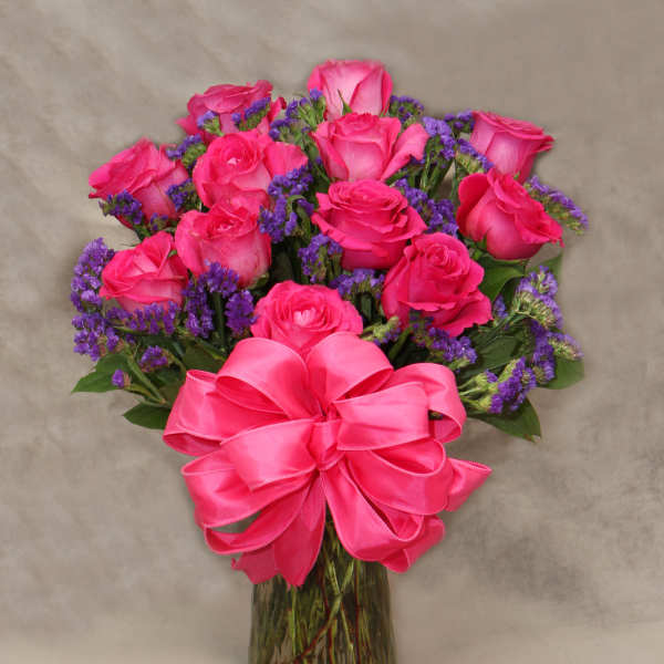 Pink roses in a glass vase with a large pink bow