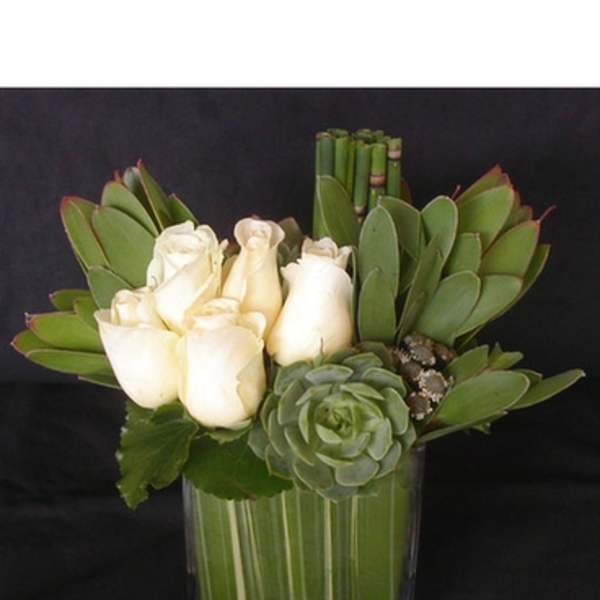 White roses and a green succulent in a glass vase
