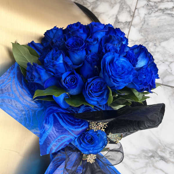 Bouquet of vivid blue roses wrapped in blue and black paper