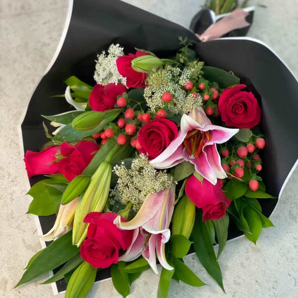 Bouquet of pink roses and lilies wrapped in black paper