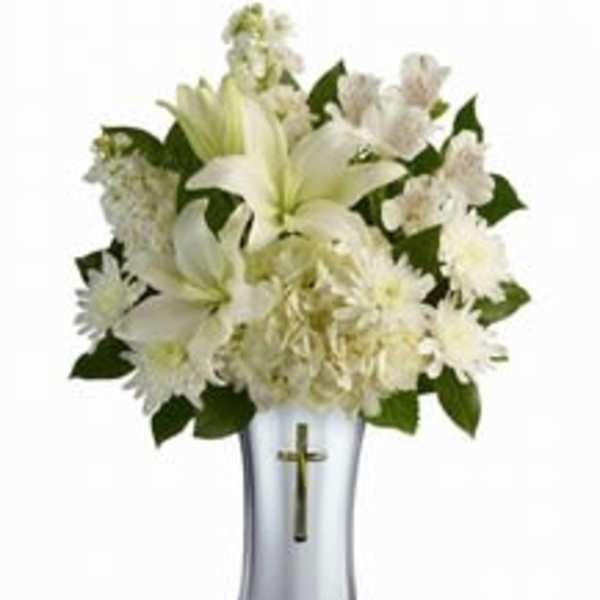 White floral arrangement in a silver vase with a cross emblem