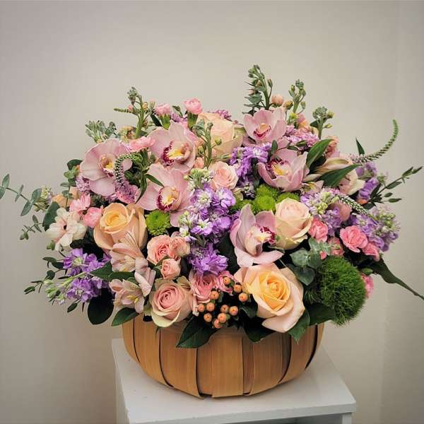 Large pastel flower arrangement in a wooden basket
