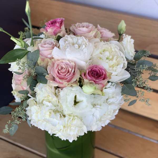 Pink and white roses with white blooms in a green glass vase