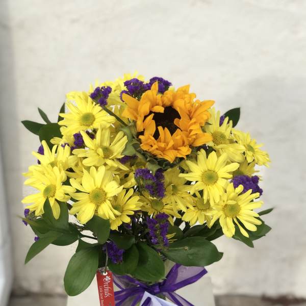 Yellow daisies and an orange sunflower bouquet in a glass vase