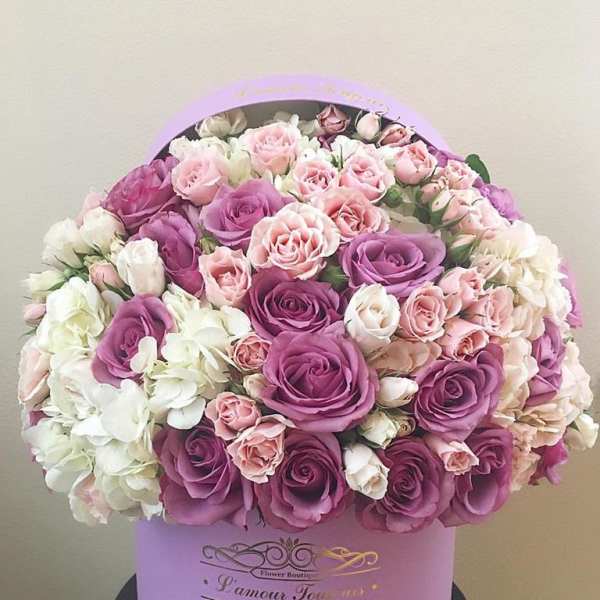 Pink and purple roses with white flowers in a lavender hat box