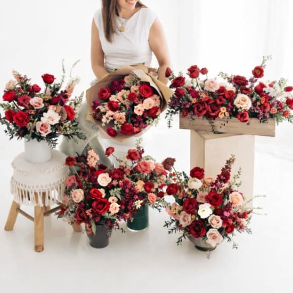 Assorted red and blush rose arrangements with a woman holding a bouquet