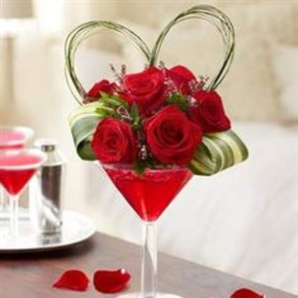 Red roses arranged in a martini glass with heart-shaped wire handles