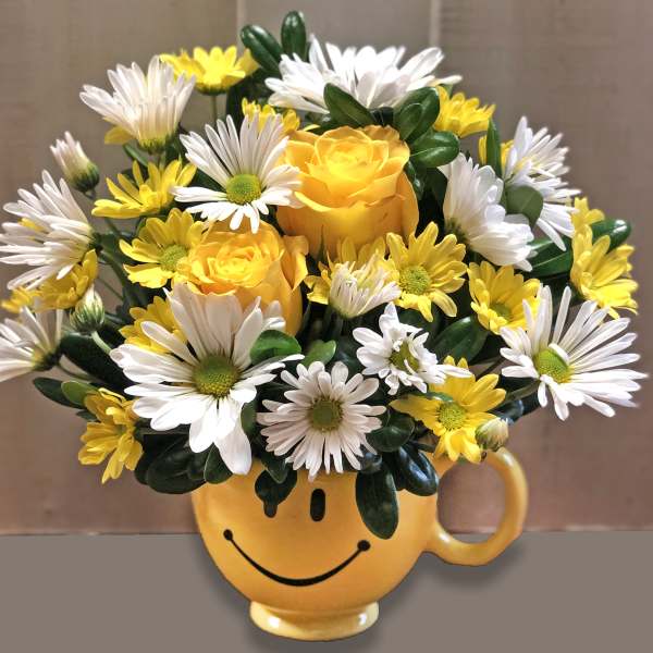 Yellow and white flower bouquet in a smiley-face mug