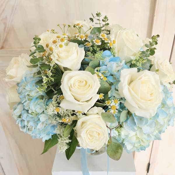 Bouquet of white roses and blue hydrangeas in a clear vase