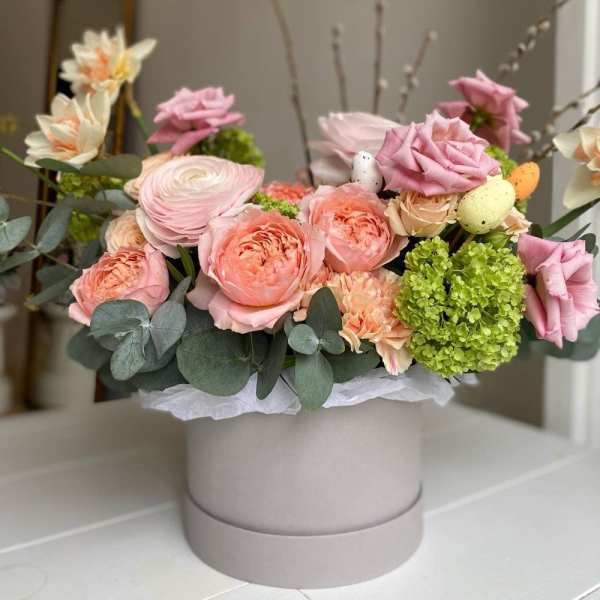 Pink and peach flower arrangement in a round hatbox