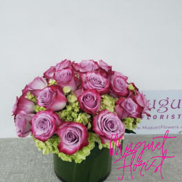 Pink roses arranged in a dark green box with pale green filler flowers.