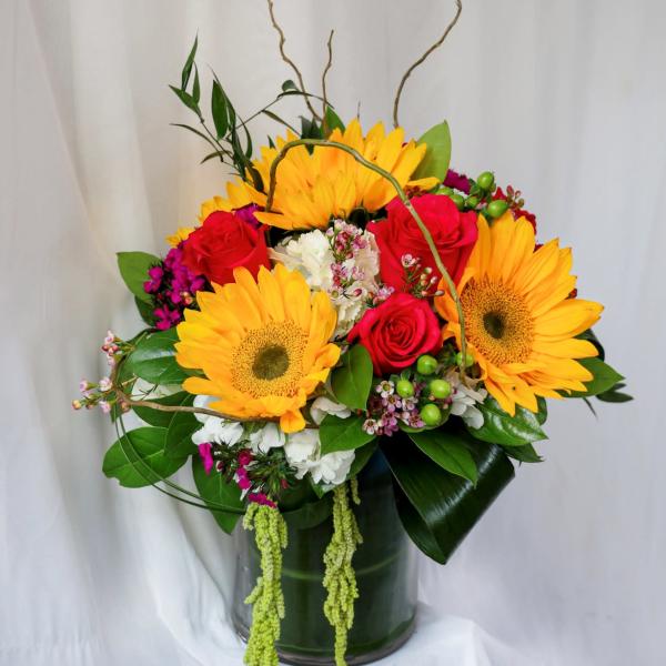 Bright bouquet of sunflowers and red roses in a glass vase