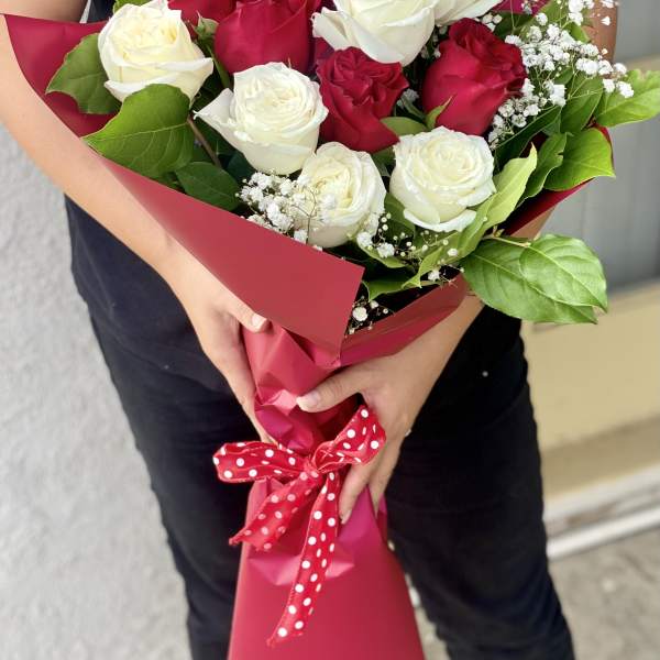 Bouquet of red and white roses wrapped in pink paper with a polka-dot ribbon