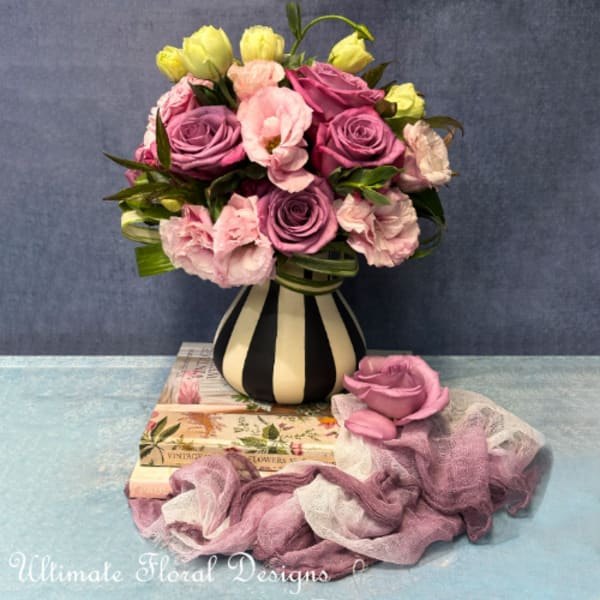 Bouquet of pink and purple roses with pale yellow blooms in a striped vase