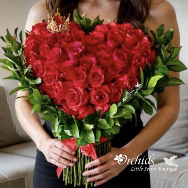 Heart-shaped bouquet of red roses with green foliage and a red ribbon