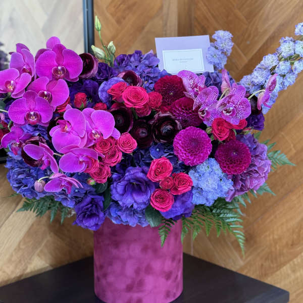 Large purple and pink floral arrangement in a magenta vase