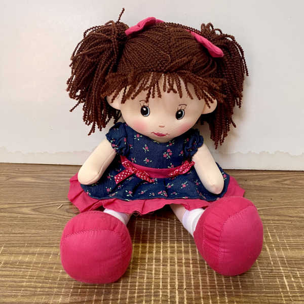 Plush doll with brown yarn hair, blue dress, and pink shoes