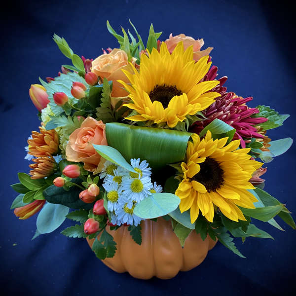 Mixed bouquet in a pumpkin-shaped container with sunflowers and roses