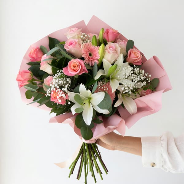 Pink and white mixed bouquet with roses, lilies, and gerbera daisies wrapped in pink paper