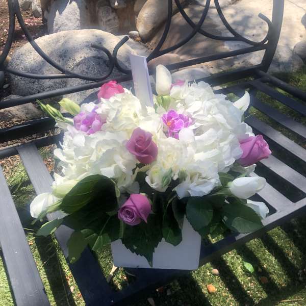 Pink and white floral arrangement in a white box