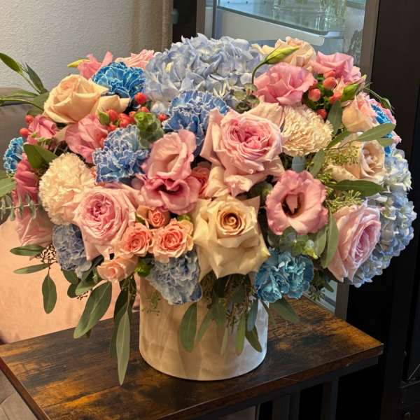 Large pastel bouquet of roses, hydrangeas, and carnations in a white hatbox