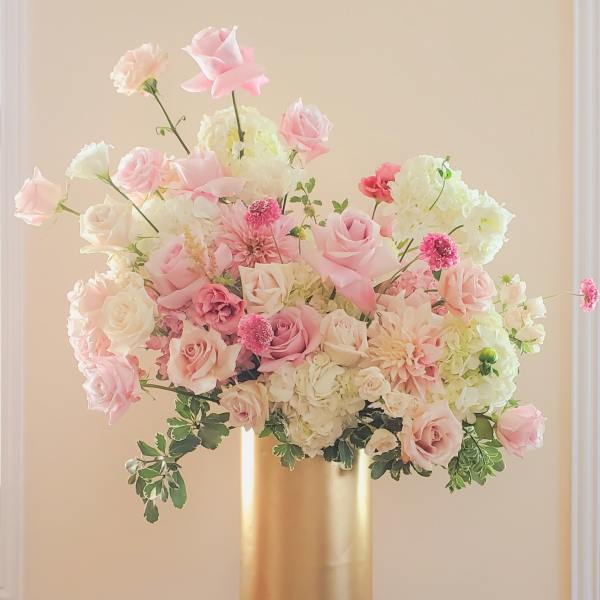 Pink and white floral arrangement in a gold pedestal vase